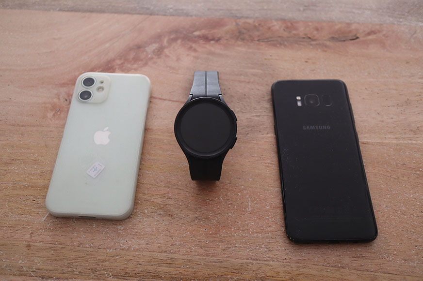 Man sieht die Galaxy Watch 5, ein iPhone und ein Samsung Handy.